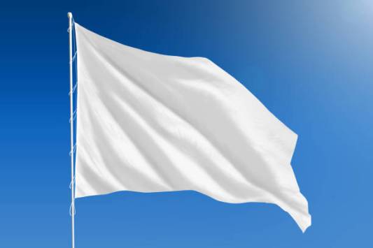 White flag blowing in the wind in front of a clear blue sky